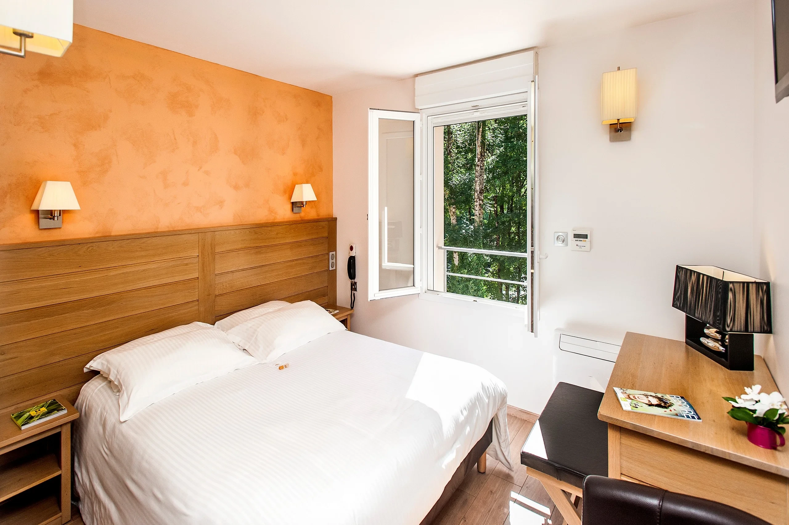 Chambre d'hôtel lumineuse avec lit et vue sur la forêt
