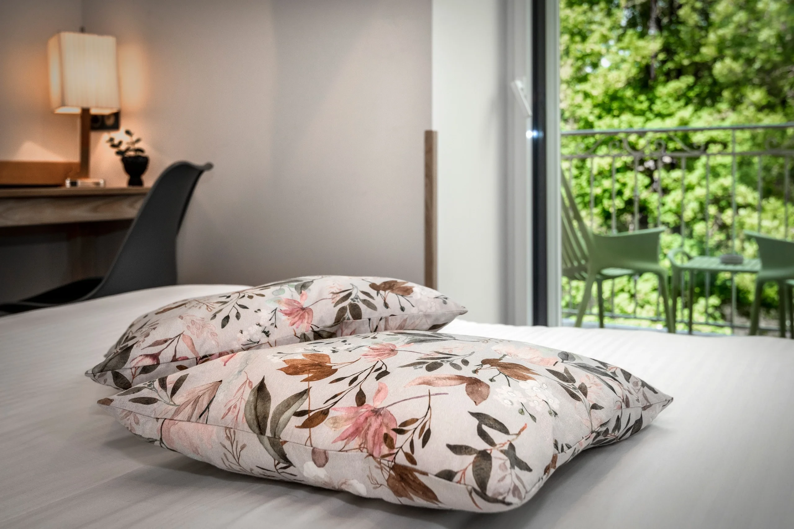 Chambre avec lit et oreillers fleuris âmeublement vert balcony